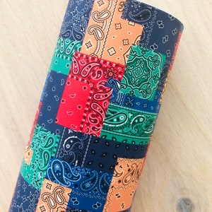 May include: A close-up of a fabric with a patchwork design featuring various shades of blue, red, green, and orange. The fabric is made up of squares with a paisley pattern.