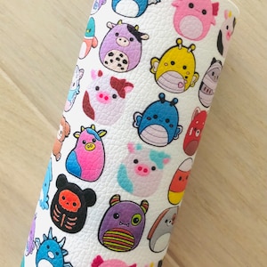 May include: White fabric with a repeating pattern of colorful cartoon characters. The characters are various animals, including a pig, a cow, a dragon, a monster, and a cat. The fabric has a textured surface.