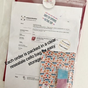 May include: A close-up of a small, clear resealable cello bag with a colorful autumn-themed design. The bag contains two small, square pieces of fabric, one blue and one pink. The text "Each order is packed in a clear resealable cello bag for easy storage." is visible on the image.