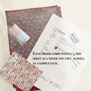 May include: A close-up of a pink and gray patterned fabric sheet with a smaller sample sheet of a colorful fabric with a fall theme. The text "EACH ORDER COMES WITH 1/4 SIZE SHEET AS A THANK YOU GIFT, AS WELL AS A SAMPLE PACK." is printed on a white sheet of paper.