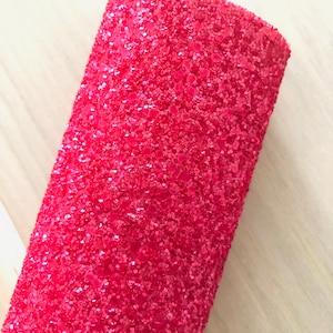May include: A close-up of a pink glitter fabric. The fabric is made of small, sparkly sequins that are tightly packed together.