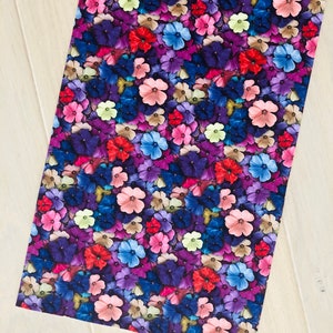 May include: A seamless fabric pattern featuring a close-up of a variety of colorful flowers. The flowers are in shades of pink, purple, blue, red, and yellow. The background is a dark purple.