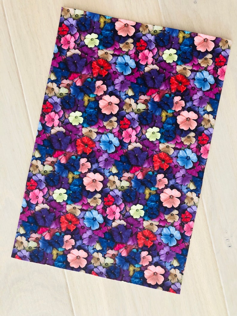 May include: A seamless fabric pattern featuring a close-up of a variety of colorful flowers. The flowers are in shades of pink, purple, blue, red, and yellow. The background is a dark purple.