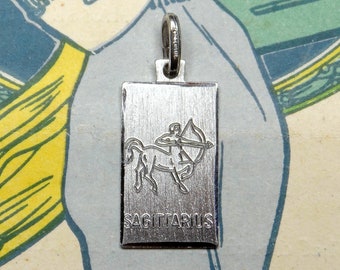 May include: Silver charm pendant with a Sagittarius zodiac sign, featuring a centaur with a bow and arrow, and the word "SAGITTARIUS" engraved below.