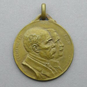 May include: A bronze medal commemorating the end of World War I, featuring profiles of French leaders Georges Clemenceau and Ferdinand Foch. The medal is inscribed with "1917-1919" and "PARIS-ART".