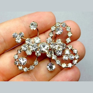Peut inclure: Une broche vintage au design délicat avec un groupe de strass clairs sertis dans un métal doré.