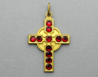 May include: A gold Celtic cross pendant with red gemstone accents. The cross is intricately detailed and has a circular halo around the center.