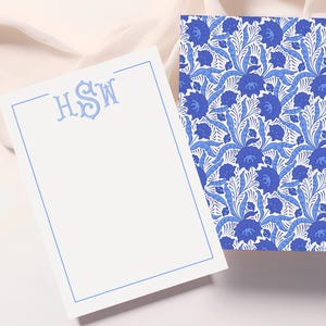 May include: Two stationery items: a notepad and a patterned card. The notepad has a light blue border and monogram initials "HSW". The card features a blue floral pattern on a white background. The items are on a white surface.