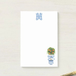 May include: A white notepad with a blue monogram "MM" at the top and a watercolor illustration of a small orange tree in a blue and white patterned pot with a blue ribbon.