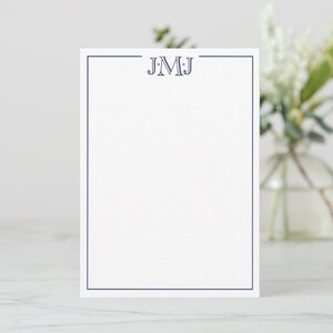 May include: White stationery with a navy blue border and monogram. The monogram features the letters "JMJ" in a decorative font, centered at the top. The stationery is rectangular and stands upright.