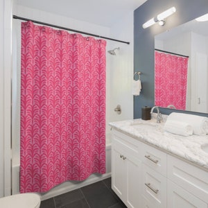 May include: A pink shower curtain with a geometric pattern. The curtain is hung in a bathroom with a white vanity and a marble countertop.
