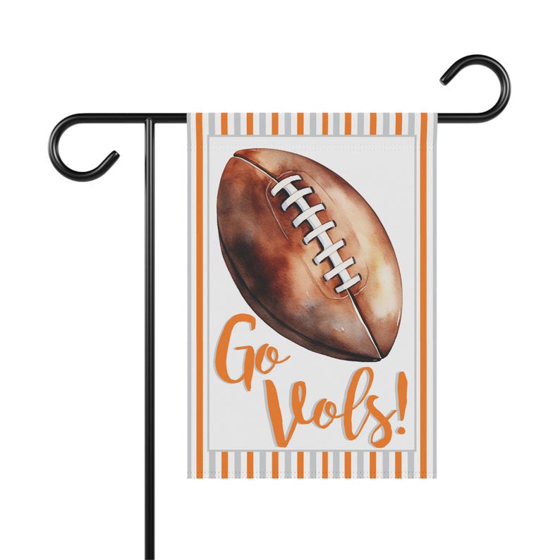 Puede incluir: Una bandera de jard&iacute;n con un bal&oacute;n de f&uacute;tbol de estilo acuarela en tonos marr&oacute;n y blanco. La bandera tiene un fondo blanco con las palabras "Go Vols!" en escritura naranja. La bandera est&aacute; bordeada por rayas naranjas y grises.
