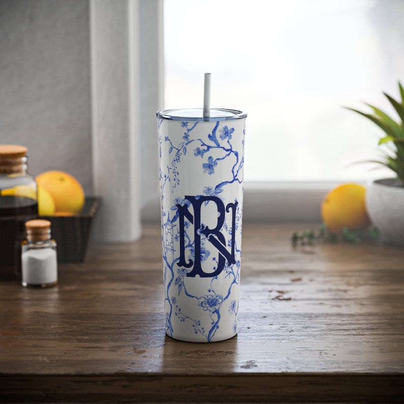 May include: A white and blue patterned stainless steel tumbler with a blue monogram "NB" and a white straw.
