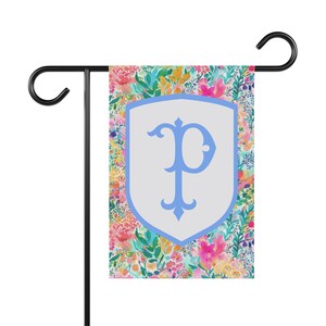 Peut inclure: Un drapeau de jardin avec un motif floral dans des tons de rose, jaune et vert. Un bouclier blanc avec une lettre "P" bleue est au centre du drapeau.
