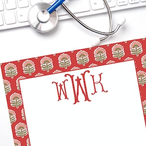 May include: Red stationery with a white border and a floral pattern. The monogram "WWK" is printed in red in the center of the white area.