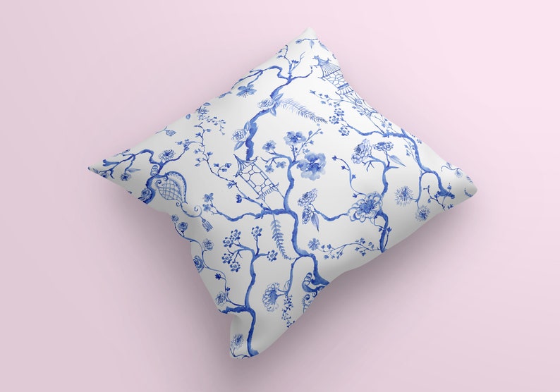 May include: A white throw pillow with a blue and white floral pattern. The pattern features branches with flowers and leaves, as well as a small bird and a pagoda.