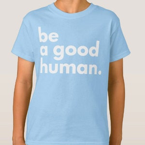 May include: Light blue t-shirt with the text "be a good human." printed in white.