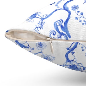 May include: A white pillow with a blue and white floral pattern. The pillow has a zipper closure.