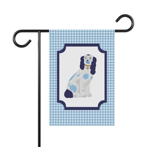 May include: A blue and white gingham garden flag with a blue framed illustration of a white dog with blue spots sitting on a white background.