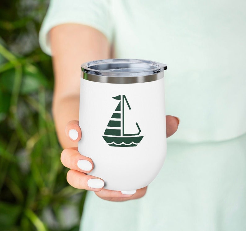 K&ouml;nnte beinhalten: Ein wei&szlig;er Edelstahlbecher mit einer gr&uuml;nen Segelbootgrafik. Der Becher hat einen Deckel.