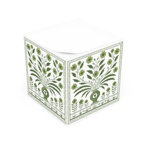 May include: A white cube-shaped notepad with a green floral design. The design features a vase with flowers and leaves, framed by a decorative border. The notepad is a practical and stylish office accessory.