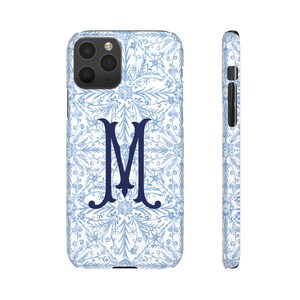 May include: A white phone case with a blue floral pattern and a navy blue letter "M" in the centre.