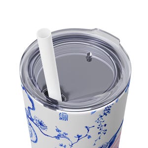 May include: A white stainless steel tumbler with a blue and white floral design. The tumbler has a clear lid with a hole for a straw. A white straw is inserted through the hole in the lid.