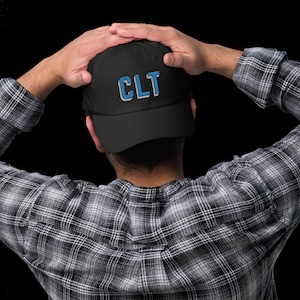 May include: A black baseball cap with a blue and white embroidered "CLT" logo.