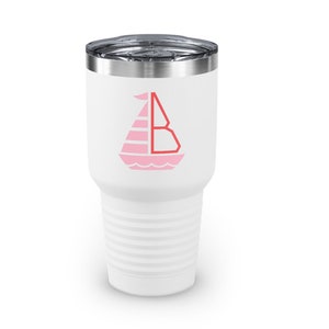 K&ouml;nnte beinhalten: Ein wei&szlig;er Edelstahlbecher mit einer rosa Segelbootgrafik und dem Buchstaben "B" in Rot. Der Becher hat ein geripptes Design.