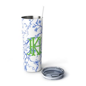 May include: A white stainless steel tumbler with a blue and white floral pattern and a green monogram "KA". The tumbler has a clear lid and a white straw.
