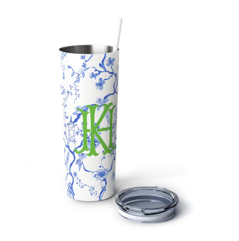 May include: A white stainless steel tumbler with a blue and white floral pattern and a green monogram "KA". The tumbler has a clear lid and a white straw.