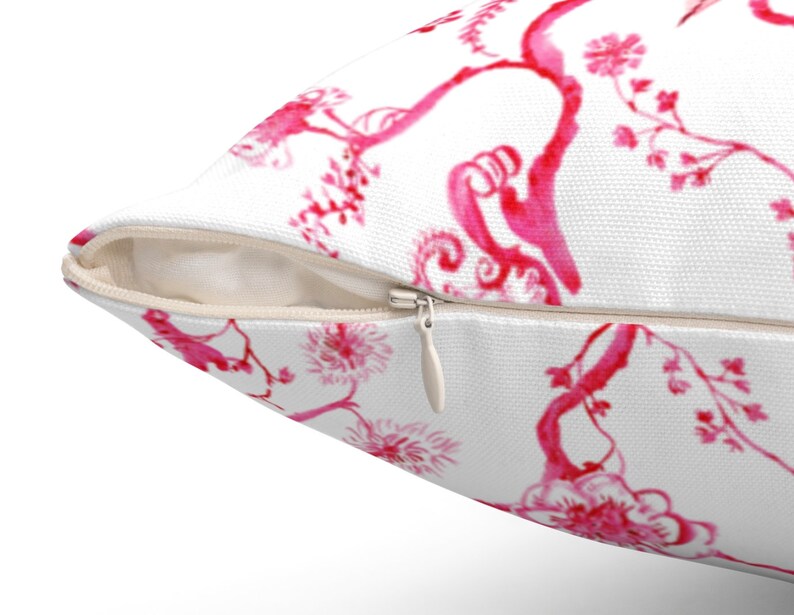 May include: White pillow cover with a pink floral pattern. The pillow cover has a zipper closure.