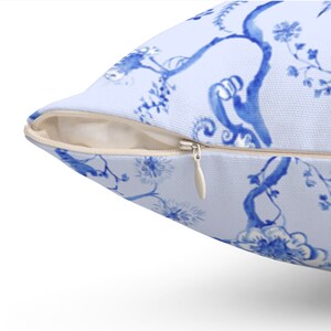 May include: A blue and white pillow cover with a floral pattern. The pillow cover has a zipper closure.
