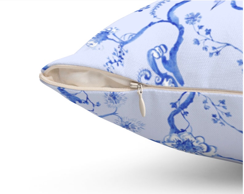 May include: A blue and white pillow cover with a floral pattern. The pillow cover has a zipper closure.