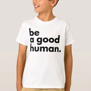 May include: White t-shirt with black text that reads "be a good human."