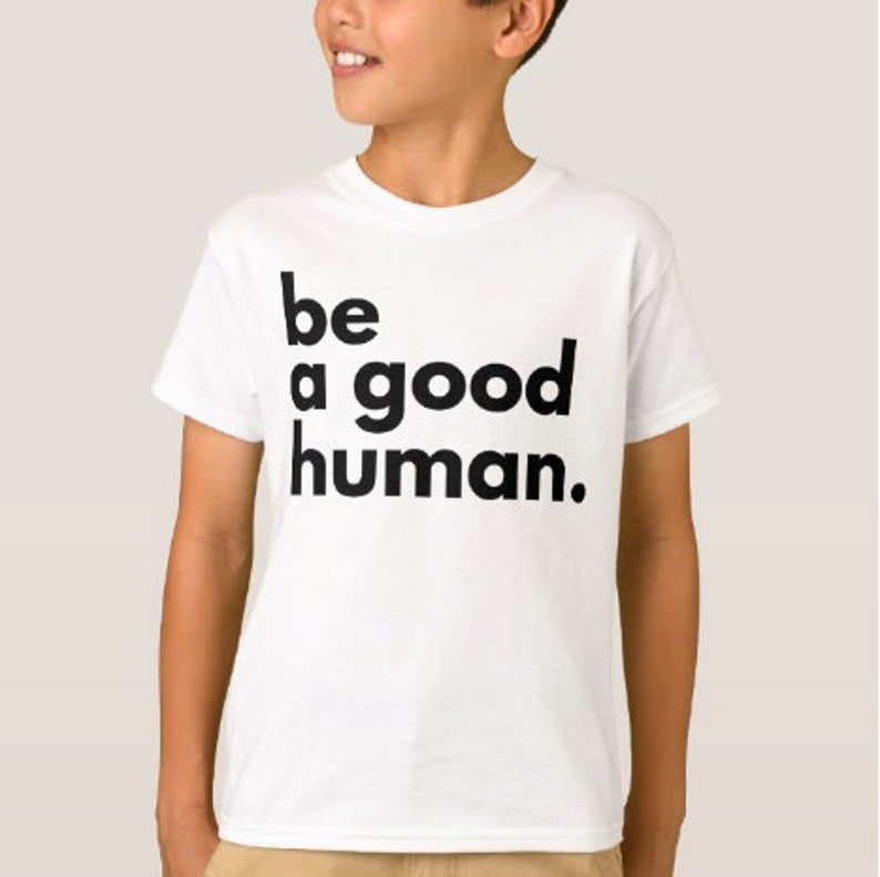 May include: White t-shirt with black text that reads "be a good human."