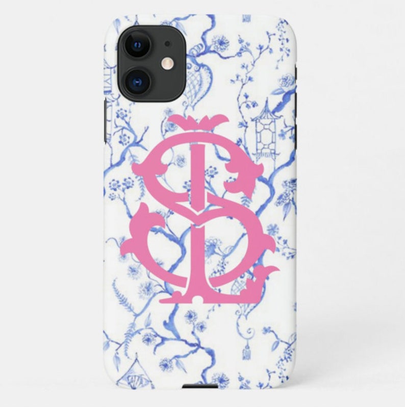 May include: A white iPhone case with a blue and white floral pattern and a pink monogram "IS".