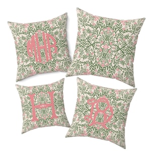 May include: Four square throw pillows with a floral pattern in green and pink on a cream background. Each pillow features a large pink monogram letter or letters: MHR, H, and RB.
