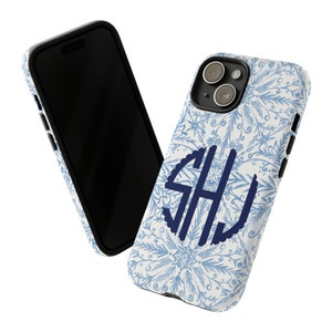 May include: A white phone case with a blue snowflake pattern and a navy blue monogram "SHJ" in a circle. The case is designed for an iPhone.