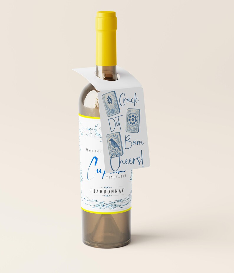 May include: A clear wine bottle with a yellow cap and a white tag. The tag has the words "Crack Dot Bam Cheers!" and blue illustrations. The bottle label says "Cupcake Vineyards Chardonnay".