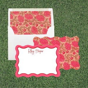 May include: A white envelope with a pink and tan floral patterned liner and a matching scalloped-edge note card featuring the name Riley Hooper in red script. The stationery set displays a repeating botanical print of flowers and leaves.