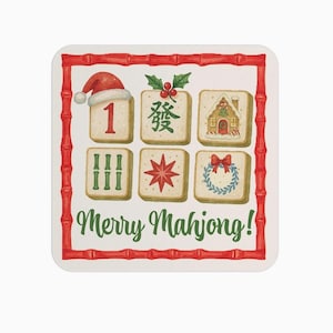 Puede incluir: Posavasos cuadrado con borde de bamb&uacute; rojo y el texto "Merry Mahjong!" en verde. El posavasos presenta seis fichas de Mahjong ilustradas con dise&ntilde;os navide&ntilde;os, incluyendo un gorro de Pap&aacute; Noel y una casa de jengibre.