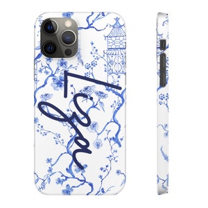 May include: A white phone case with a blue and white floral pattern and the name "Lisa" written in blue cursive. The case has a raised camera bump and a cutout for the charging port.