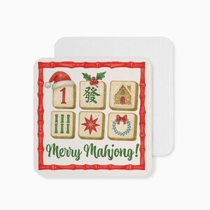 Puede incluir: Posavasos cuadrado con borde de bamb&uacute; rojo y el texto "Merry Mahjong!". El posavasos presenta ilustraciones de fichas de Mahjong, incluyendo un gorro de Pap&aacute; Noel, una casa y una corona. Un segundo posavasos es visible.
