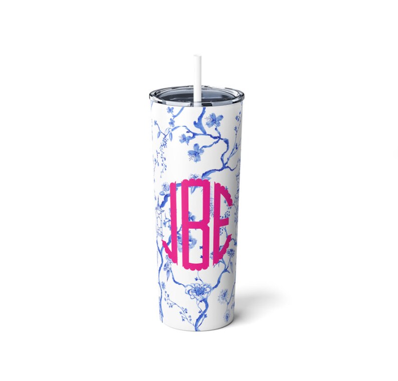 May include: A white stainless steel tumbler with a blue and white floral pattern and a pink monogram "JBE".