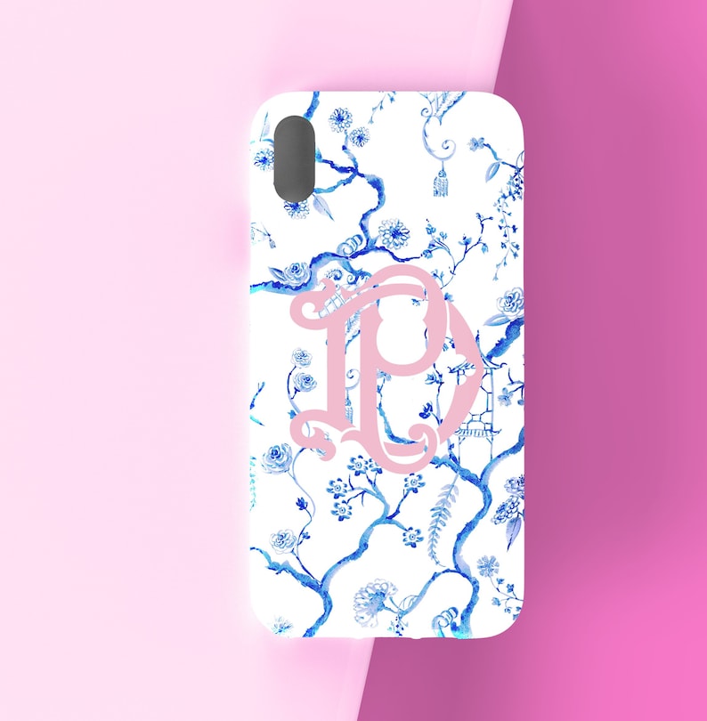 May include: A white phone case with a blue and white floral pattern and a pink letter "P" in the center.