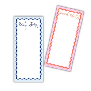 May include: Two personalized notepads with scalloped edges. One notepad has a light blue background with a dark blue border and the name "Emily Jones" in cursive. The other notepad has a pink background with an orange border and the name "Hannah Roberts" in cursive.