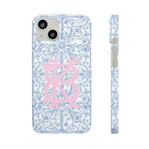 May include: A white phone case with a blue and white floral pattern and a pink monogram "KB" in the centre.