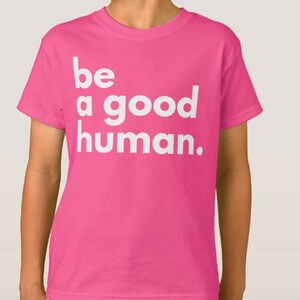 May include: Pink t-shirt with white text that reads "be a good human."