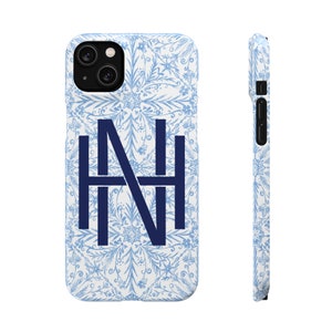 May include: A white phone case with a blue floral pattern and the letters "NH" in a navy blue colour.